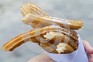Churros sprinkled with sugar held in a paper cone photo