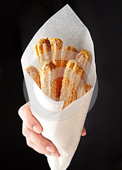 Churros traditional Spain or Mexican street fast food baked sweet dough snack in hand photo