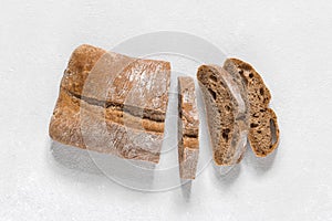 Ciabatta. Dark fresh healthy flattish open-textured Italian bread on white rustic background. Close-up. Top view