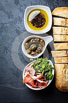 Ciabatta, pepper oil, jamon ham serrano, arugula, rosemary, slate background