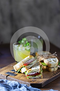 Ciabatta sandwich with turkey, lettuce, tomatoes, cheese on a wooden board