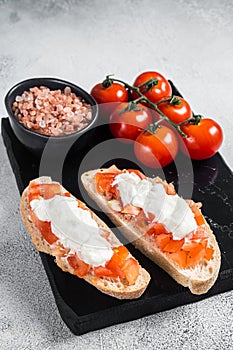 Ciabatta toasts with stracciatella cheese, chopped tomatoes and basil. White background. Top view