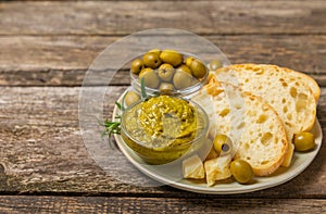Ciabattas, olive oil in a bowl with olives, herbs, spices, garlic, pesto, parmesan and ciabatta bread on a texture background.