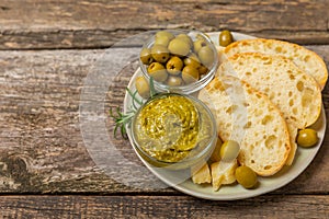 Ciabattas, olive oil in a bowl with olives, herbs, spices, garlic, pesto, parmesan and ciabatta bread on a texture background.