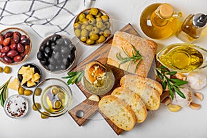 Ciabattas, olive oil in a bowl with olives, herbs, spices, garlic, pesto, parmesan and ciabatta bread on a texture background.