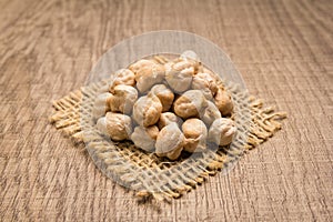 Chickpeas legume. Grains on square cutout of jute. Wooden table. photo