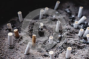 Cigarette butts on ashes, liked a graveyard, smoking kills concept, selective focus