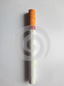 A cigarette with a distinctive red strip on the end, set against a white background. photo