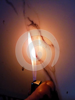 Cigarette lighter lighting flame in front of white tiles