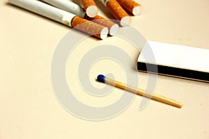Cigarette and matches on a white background. Yellow filter. Harm to health. It's a bad habit. The vision of a world without