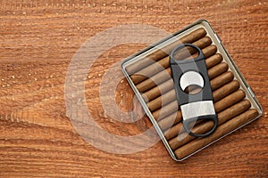 Cigars and guillotine cutter on wooden table, top view. Space for text