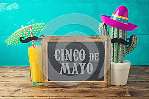 Cinco de Mayo holiday background with chalkboard, Mexican cactus, party sombrero hat and orange juice photo