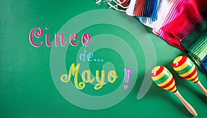 Cinco de Mayo holiday background made from maracas, mexican blanket stripes or poncho serape on green background