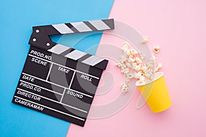 Cinema clapperboard and popcorn in paper bag on pink blue colorful background - Movie cinema entertainment