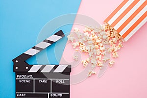 Cinema clapperboard and popcorn in paper bag on pink blue colorful background - Movie cinema entertainment