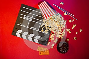 Cinema concept. Clapperboard, ticket and popcorn on red background