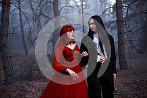 Cinema grain added old film style. Romantic gothic couple in motion walking in deep forest, dark tree. Gothic love