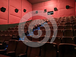 Cinema - interior of a movie theatre with empty red and black seats with white screen