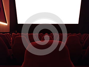 Cinema - interior of a movie theatre with empty red and black seats with white screen - mock-up screen