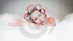 Cinemagraph of blond woman with curlers lying in hot bathtub