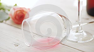 Cinemagraph - Glass with red wine and rose flower on wooden background.