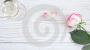 Cinemagraph - Glass with white wine and rose flower on wooden background.
