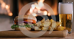 Cinemagraph - Hamburger with potatoes and beer on the fireplace background.