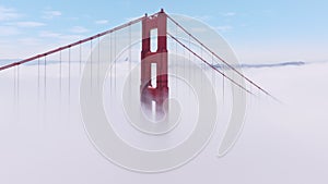 Cinematic aerial heavy white fog surrounding tall red towers Golden Gate Bridge