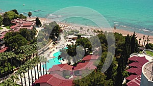 Cinematic aerial shot of vacation hotel resort with beautiful pool on idyllic summer sea coast beach at Side, Turkey.