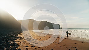 Cinematic beach with surfer woman walk with board