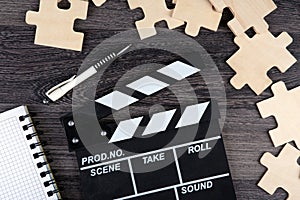 Cinematic  clapper with notepad, pen and puzzle pieces on a table