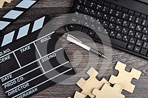 Cinematic  clapper, pc keyboard, pen and puzzle pieces on a table