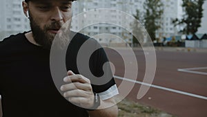 Cinematic close-up shot of young motivated bearded male athlete running on track, leading healthy lifestyle slow motion.