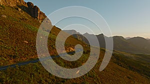 Cinematic footage of road leading around mountain ridge. Amazing evening shot of landscape in sunset time. South Africa