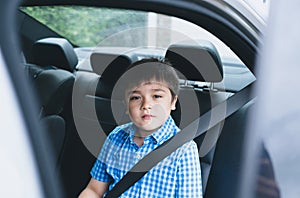 Cinematic portrait boy siting in safety car seat looking at camera with smiling face,Child sitting in the back passenger seat with