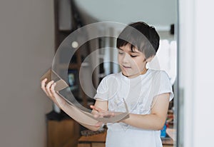 Cinematic portrait Happy young boy using cardboard for headphone toy, Active Kid with big smile while playing card box, Positive