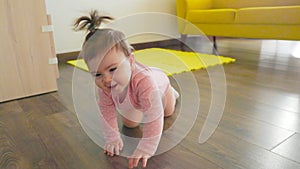 Cinematic shot of a cute happy little toddler baby boy is crawling on a wooden floor at home