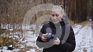 Cinematic shot, slow motion. girl photographer walks through the autumn forest and takes pictures of nature. holds a