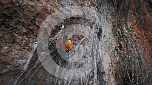 cinematic slow motion Rock climbing moments. climber in yellow sweatshirt on climbs up on overhanging cliff. Male