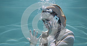 Cinematic under water portrait of angry stressed young redhead business woman shouting talking on phone call slow motion