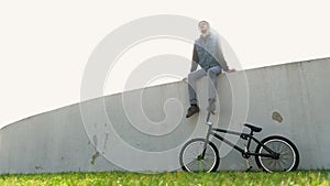 Cinematograph young man with bicycle on green grass sitting in back light