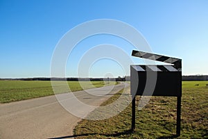 Cinematographic clipboard that stand on the road. Blank clapper board sign that stand outside