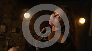 Closeup shot of brunette woman in film strips sitting on directors chair at the backstage, posing looking at the camera.