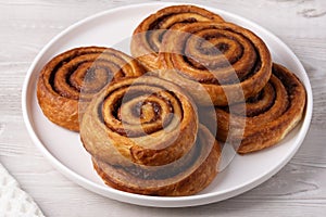 Cinnamon bun in white plate on white table