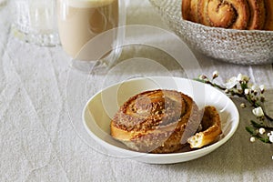 Cinnamon buns with nuts served with cappuccino on a linen tablecloth. Useful breakfast.