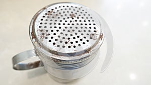 CINNAMON OR CHOCOLATE SHAKER. TOP VIEW, MESSY, USED, DINGED, HIGH USE, OLD, CLASSIC,