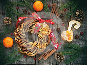 Cinnamon cocoa brown sugar wreath buns. Sweet Homemade christmas baking. Roll bread, tangerines, decoration on wooden background.