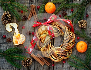 Cinnamon cocoa brown sugar wreath buns. Sweet Homemade christmas baking. Roll bread, tangerines, decoration on wooden background.