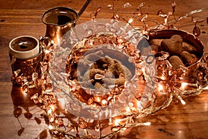 Cinnamon cookies with ginger bread, a cup of coffea and golde-pink light on wooden table