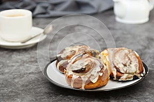 Cinnamon danish bun or cinnabons on dark background with coffee cup. Sweet homemade pastry